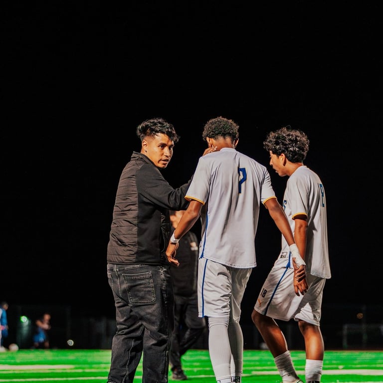 Coach speaking with football players on a brightly lit field at night during a game or practice
